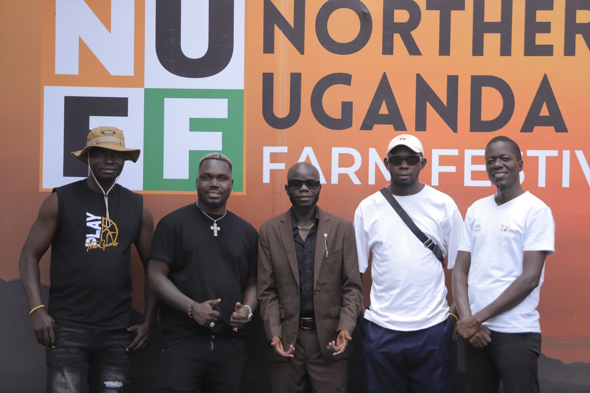 Five guests standing before the festival backdrop